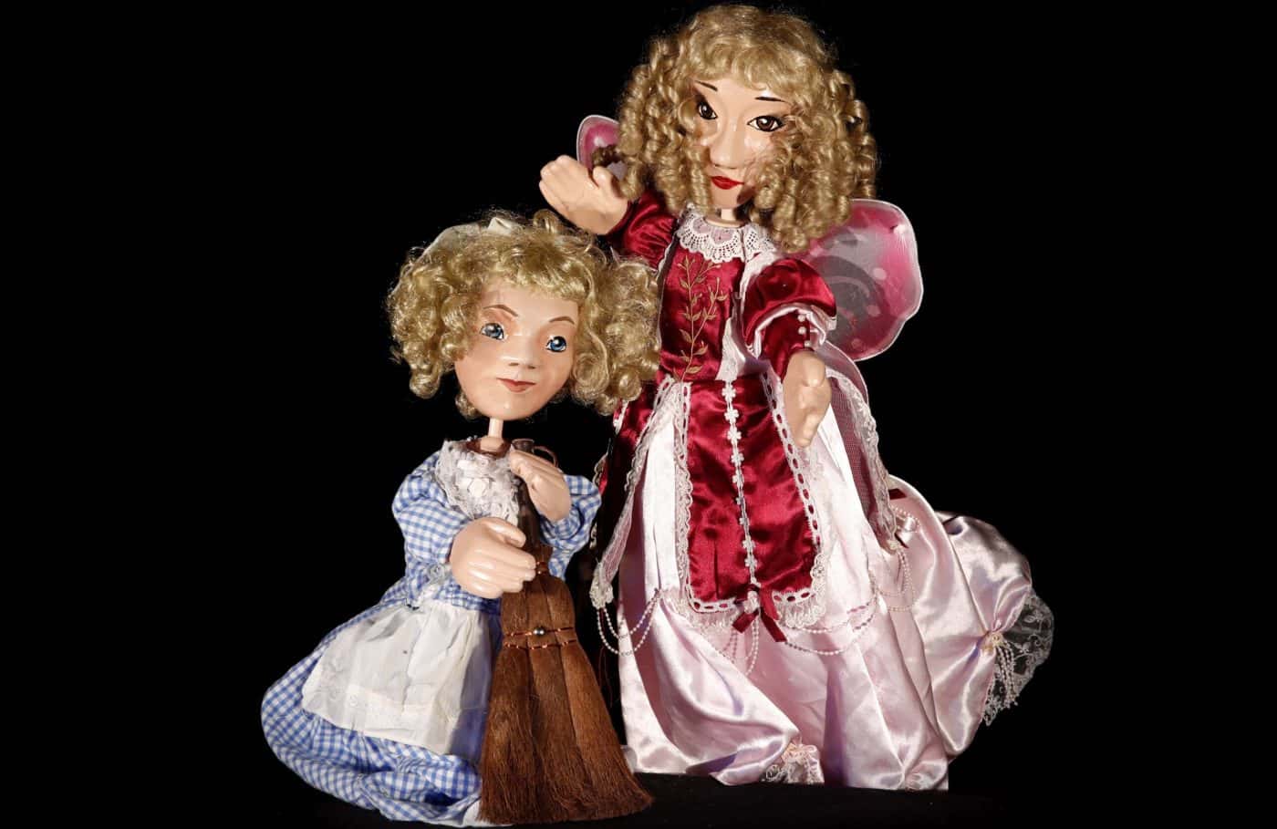 Fetițe de păpuși în costume elegante, cu păr blond și coafuri curly, pe fundal negru.