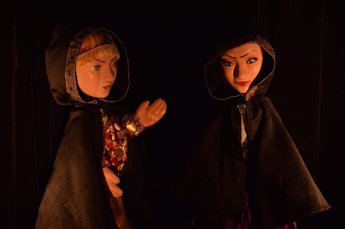 Păpuși marionete cu costume tradiționale și capete acoperite, performanță artistică.