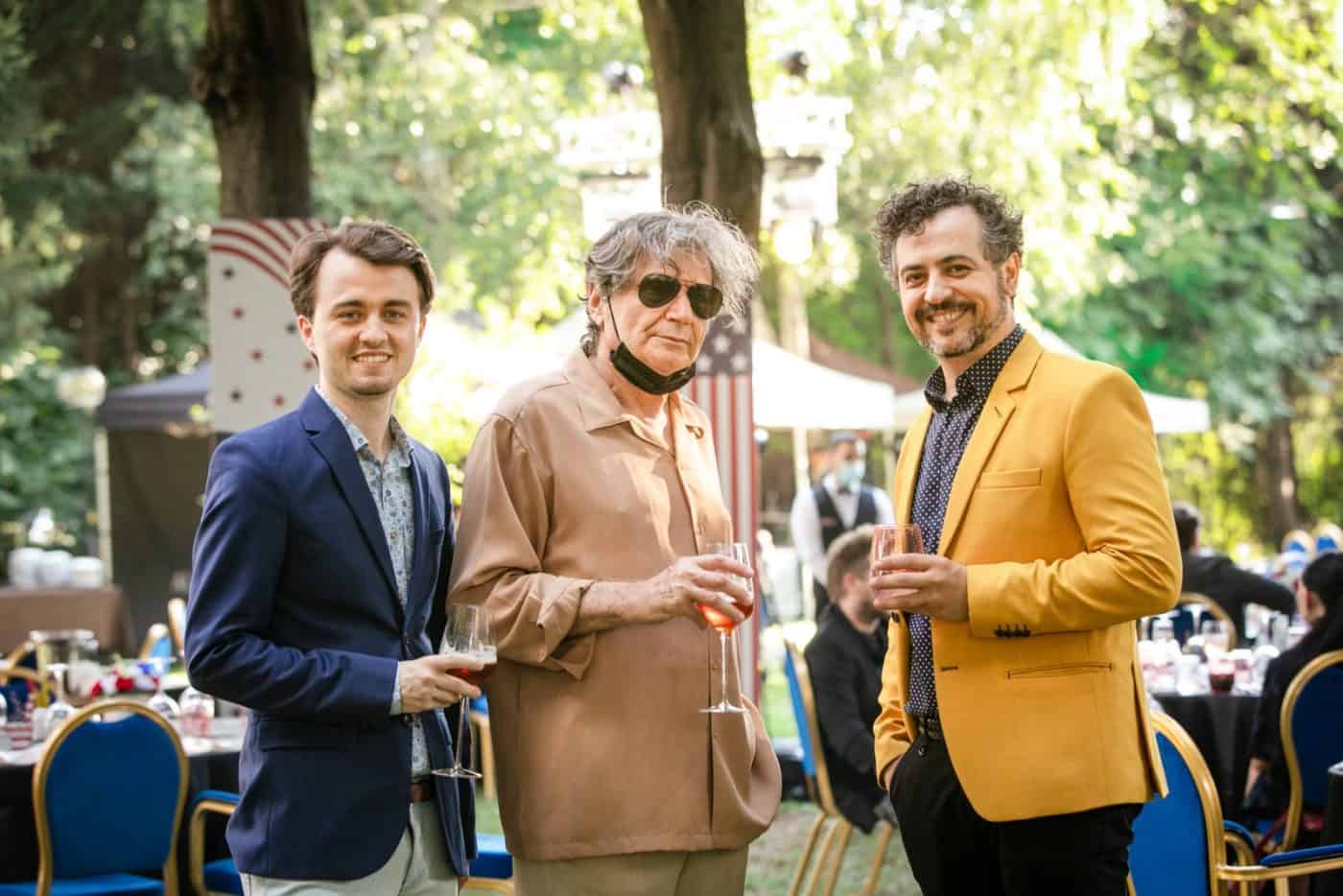 Creas, eveniment social, oameni zâmbitori, petrecere în aer liber, atmosferă relaxantă.